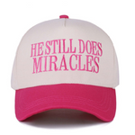 Fuchsia and white canvas cap with "He Still Does Miracles" embroidered on the front.