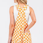 Orange checkered knit romper overalls with cuffed shorts, adjustable straps, and multiple pockets, laid flat to show texture and design.