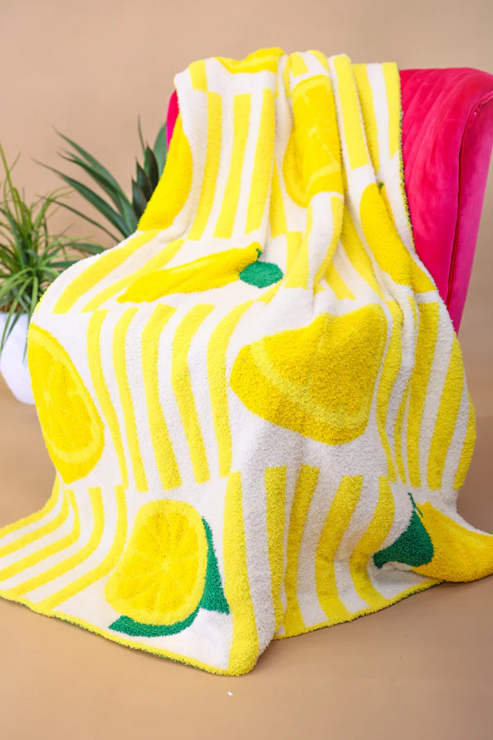 Soft blanket with playful allover lemon print in yellow and green on a white background.