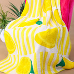 Soft blanket with playful allover lemon print in yellow and green on a white background.