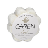 A daisy shaped, soap-infused sponge with the word "Loved" printed on the front.