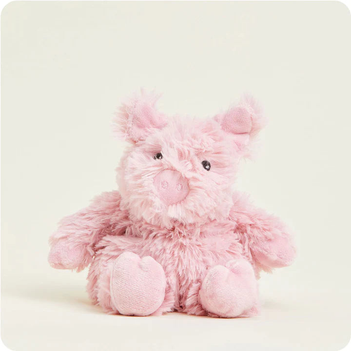 A small, soft pink plush pig toy with a curly tail and snout, designed to be microwavable.