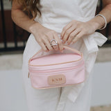 A rose Jon Hart mini makeup case with natural leather trim and a monogrammed patch.