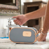 Slate-colored junior shave kit made of coated canvas with natural leather trim, shown from the front with zippered closure and leather carrying straps.