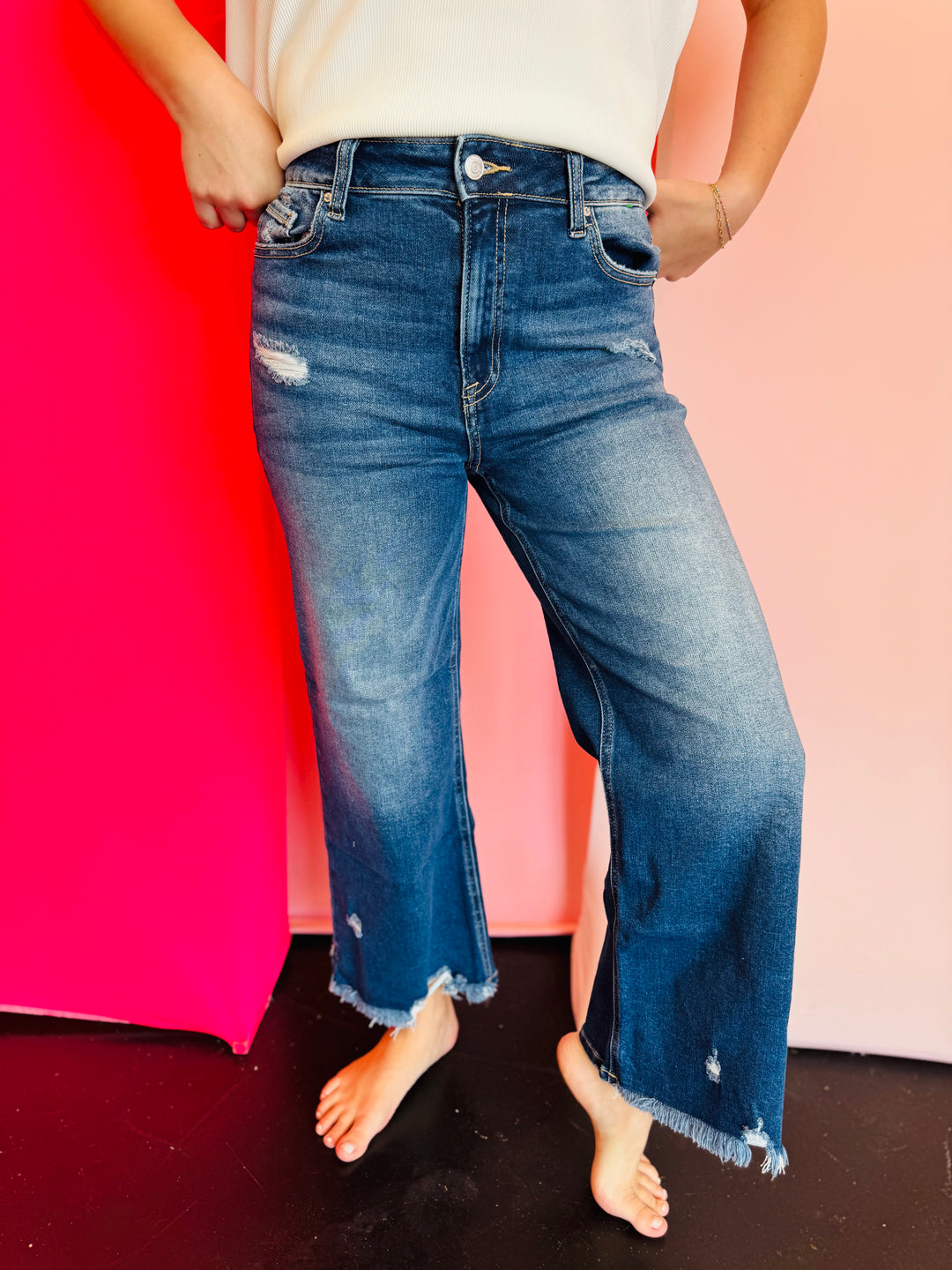 Blue denim distressed jeans that have a straight-leg fit and a raw, frayed hemline that hits above the ankle.