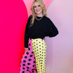 Half pink, half yellow wide-leg polka dot pants with elastic drawstring waistband and bold vibrant pattern.