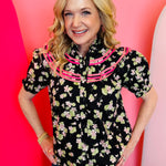 Black floral ruffle top with bib neckline, binding trim, and puff sleeves in breathable cotton.