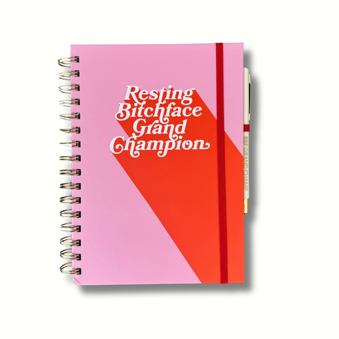 Pink and coral RBF Grand Champion journal with white lettering that says “Resting Bitchface Grand Champion,” matching pen, A5 hardcover, and 140 pages.
