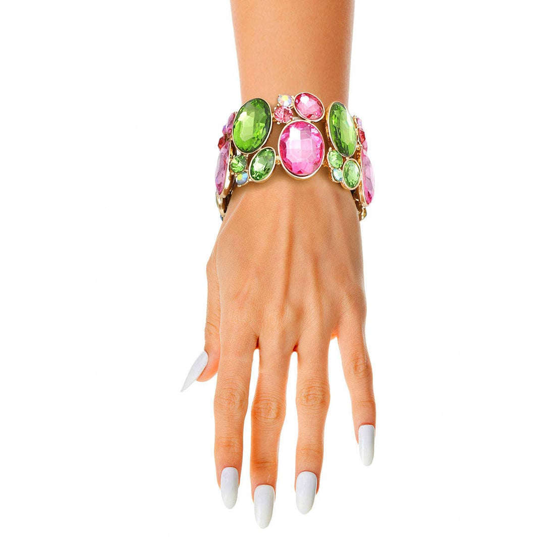 A wide gold stretch bracelet adorned with pink and green oval crystals.