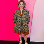 Geometric fall mini dress in orange, green, and gold with V-neck and ruffle hem.