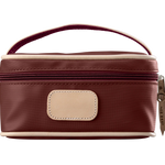 A burgundy colored Jon Hart mini makeup case with natural leather trim and a leather patch for personalization.