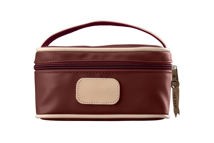 A burgundy colored Jon Hart mini makeup case with natural leather trim and a leather patch for personalization.