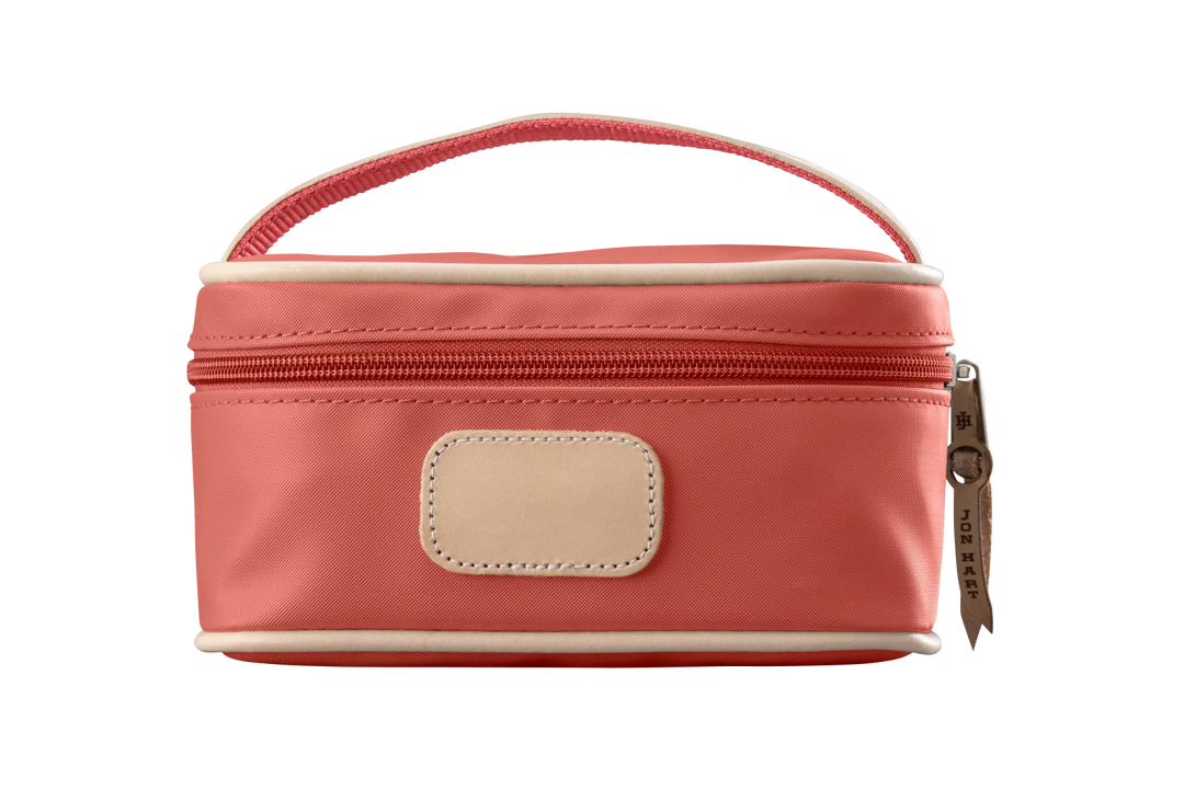 A coral colored Jon Hart mini makeup case with natural leather trim and a leather patch for personalization.