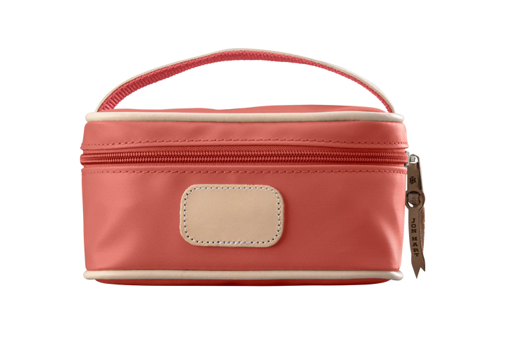 A coral colored Jon Hart mini makeup case with natural leather trim and a leather patch for personalization.