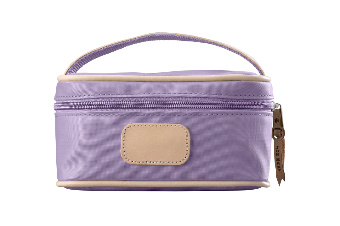 A lilac colored Jon Hart mini makeup case with natural leather trim and a leather patch for personalization.