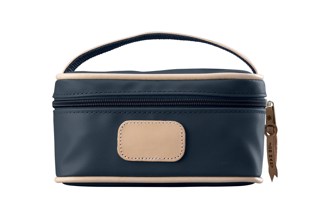 A navy colored Jon Hart mini makeup case with natural leather trim and a leather patch for personalization.