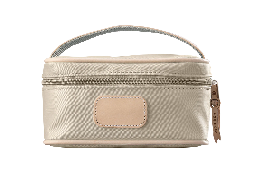 A tan colored Jon Hart mini makeup case with natural leather trim and a leather patch for personalization.