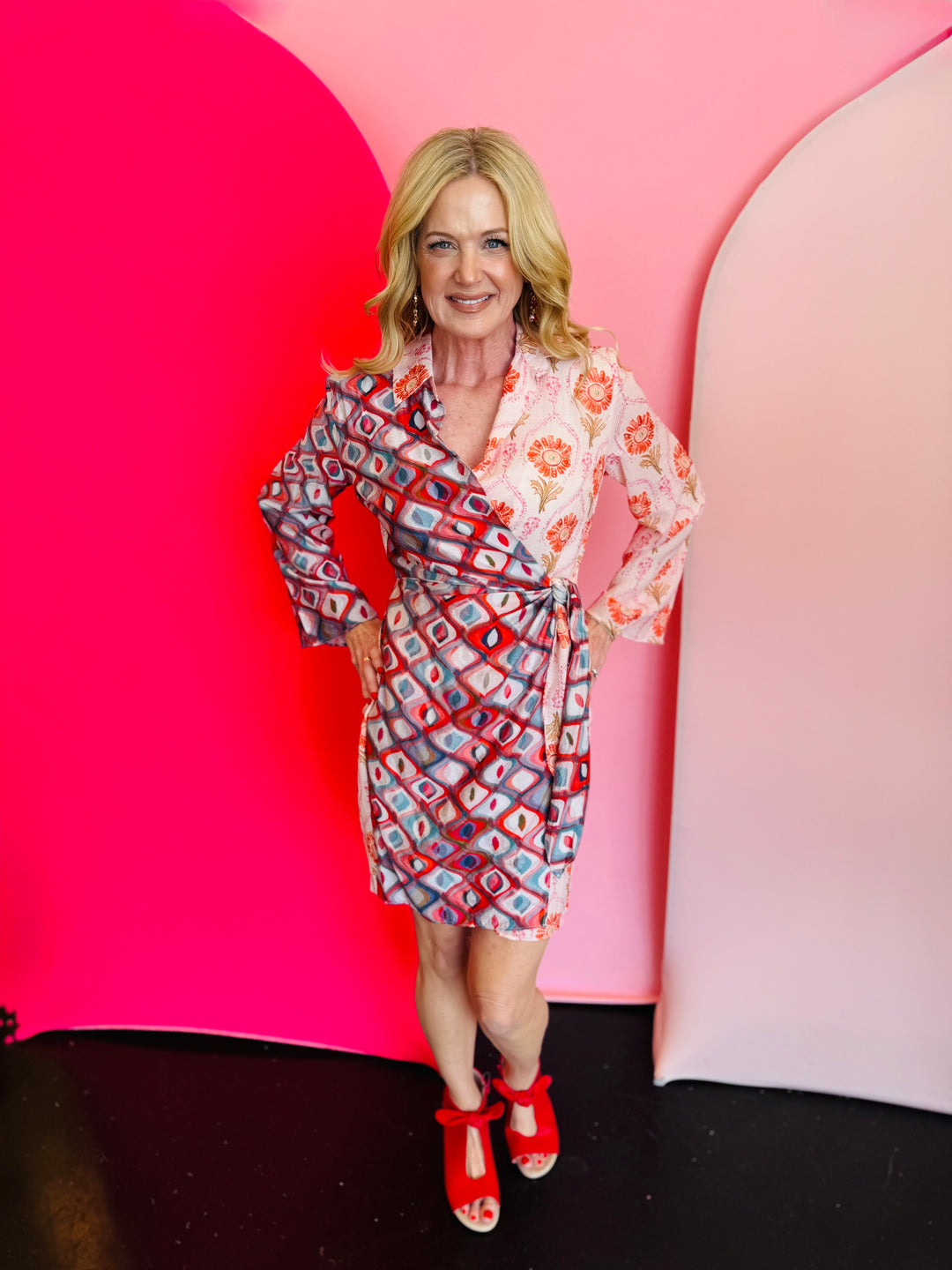 Red and coral mixed print long sleeve wrap mini dress with a collar and tie waist.