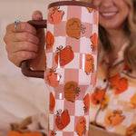 A 40 oz tumbler with a handle, featuring a repeating pattern of pumpkins and bows.