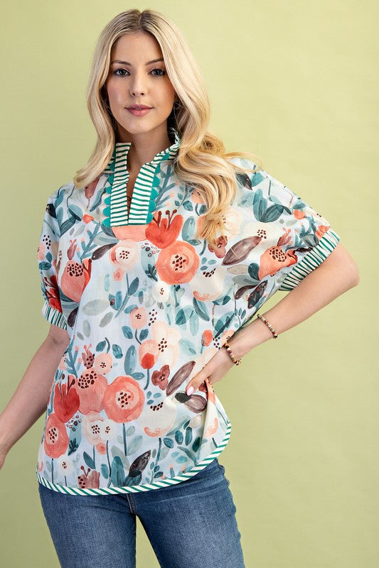 Teal mix floral mock-neck top with coral, peach, and teal blooms, striped split neckline, decorative trim, relaxed puff sleeves, and cotton/polyester blend fabrics.