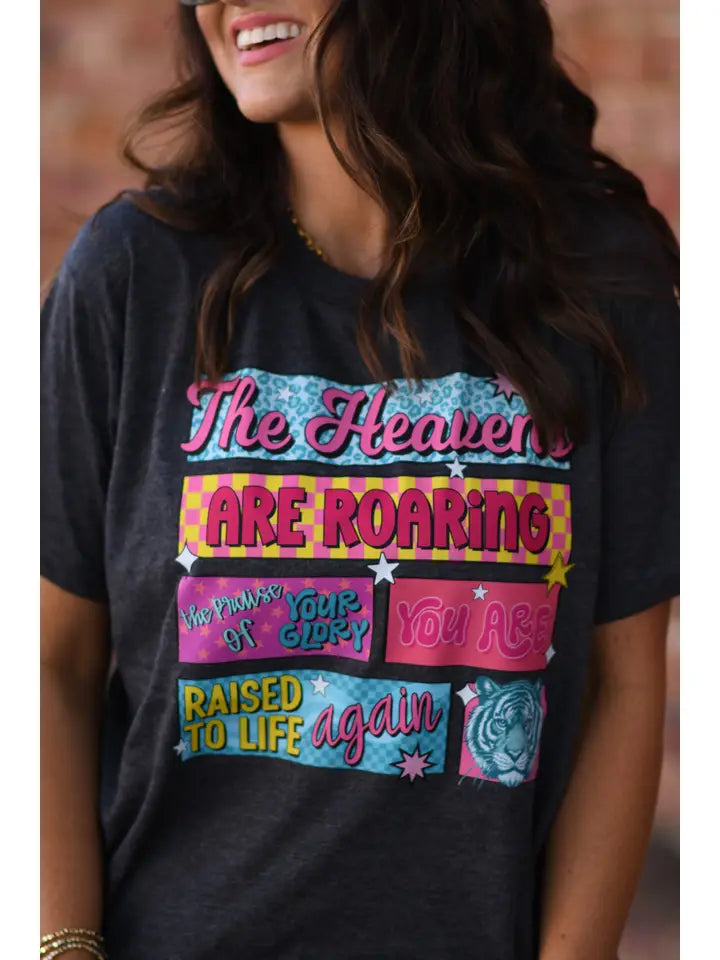Heather graphite tee with pink, yellow, and turquoise graphics, "The Heavens Are Roaring The Promise Of Your Glory You Are Raised To Life Again."