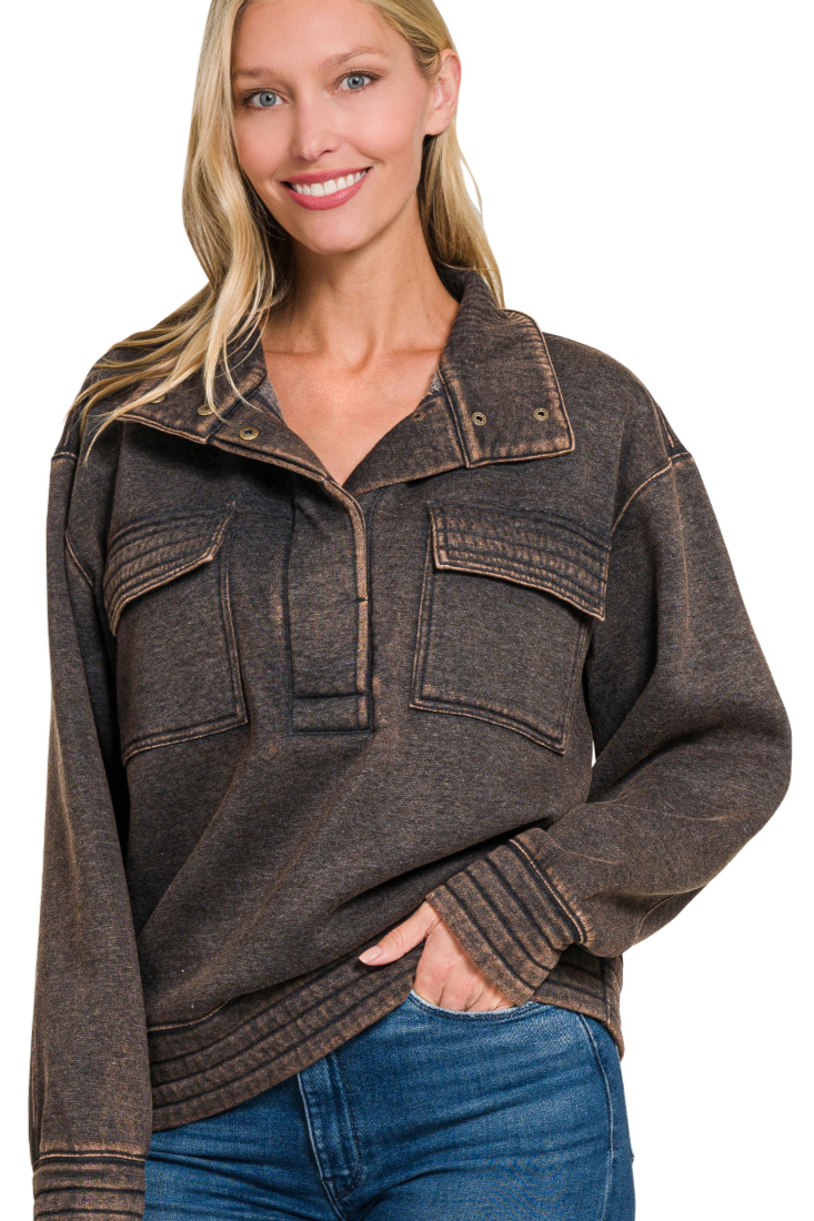 A relaxed-fit, long-sleeve fleece sweatshirt. The sweatshirt has an ash black acid-wash finish, a high collar, and a half-snap button placket at the front.