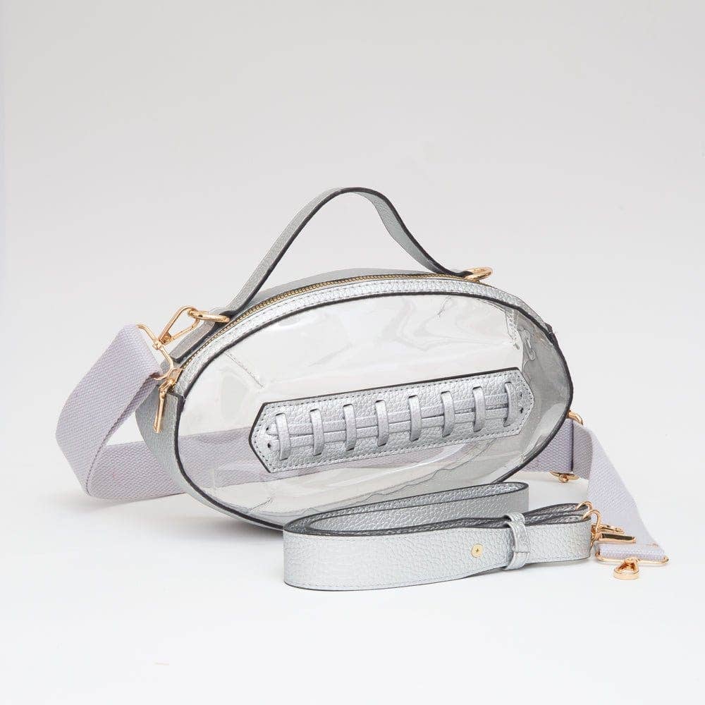 Clear football-shaped crossbody bag with silver trim, top handle, gold hardware, and adjustable strap, displayed flat to show design and size.