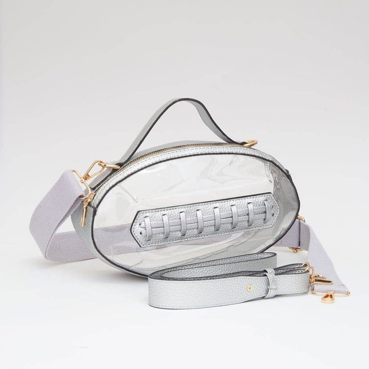 Clear football-shaped crossbody bag with silver trim, top handle, gold hardware, and adjustable strap, displayed flat to show design and size.