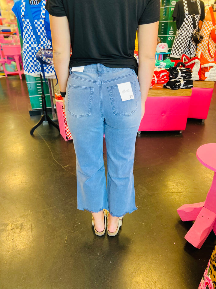back side of Blackberry colored washed cropped jeans with distressed knees and raw hem