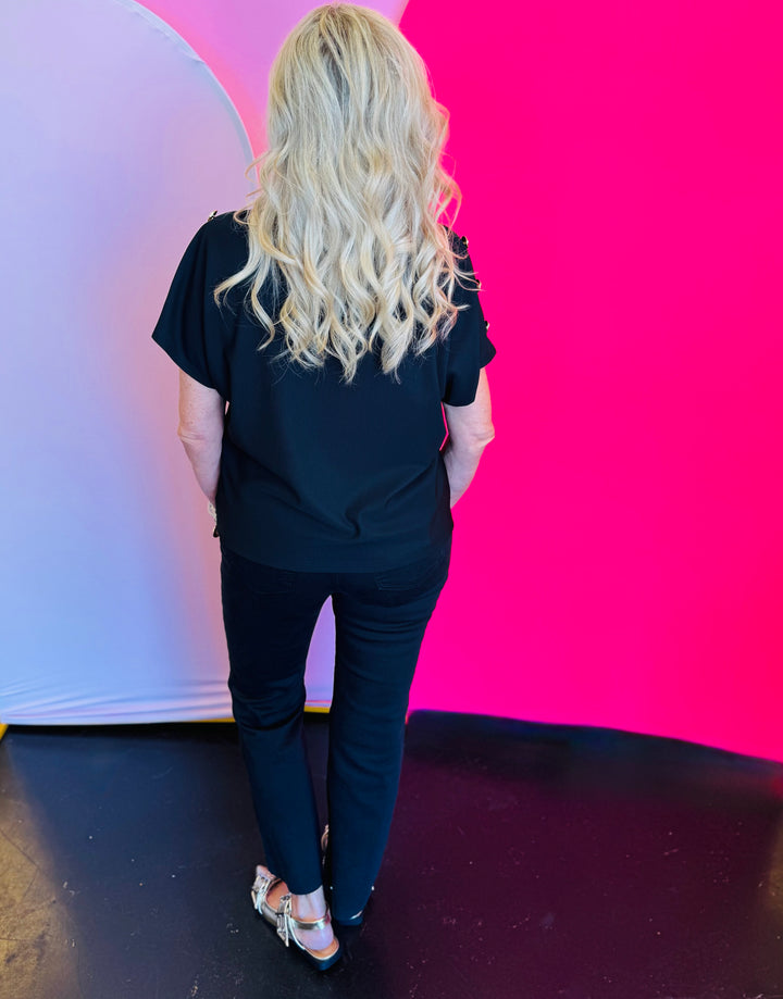 Back view of the black crewneck top showing the smooth, unembellished back and relaxed fit of the lightweight knit fabric.