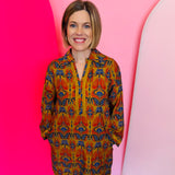 Toffee Boho Print Dress with orange, gold, and navy pattern, collared neckline, cotton braided trim, and pockets.