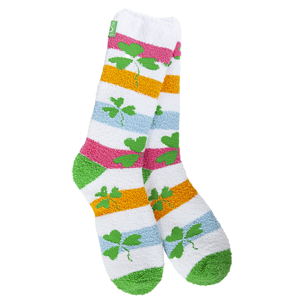 A pair of fuzzy, plush crew socks with a colorful horizontal stripe pattern. Small green shamrocks are scattered across the stripes.