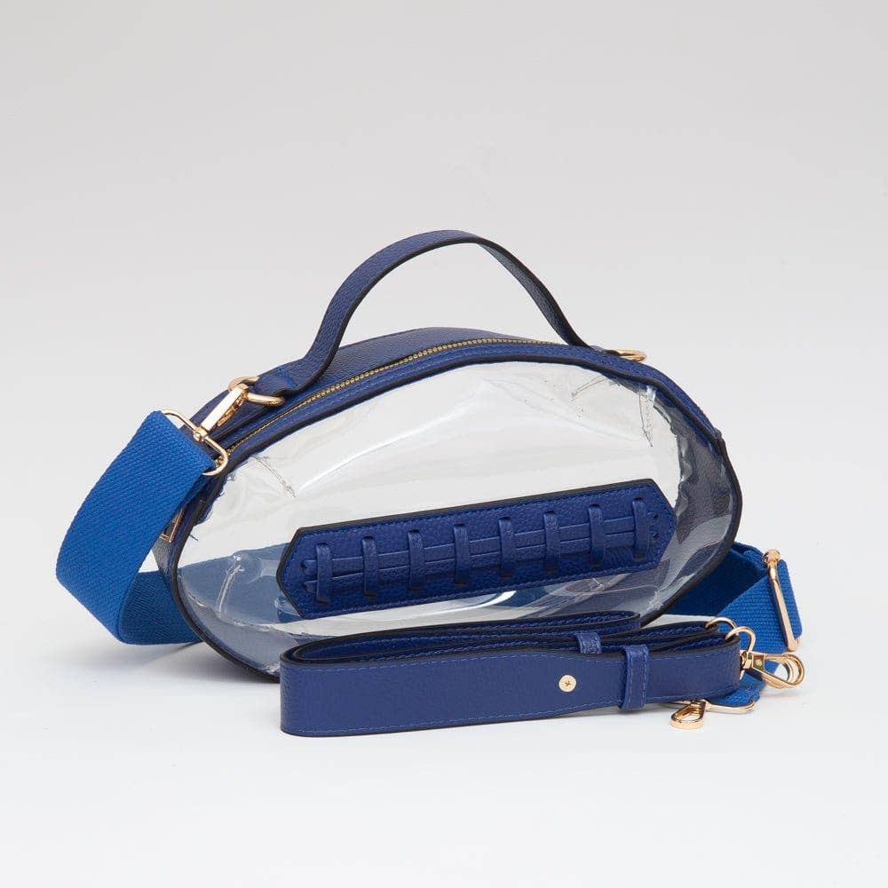 Clear football-shaped crossbody bag with royal blue trim, gold hardware, top handle, and adjustable strap, laid flat to show design and bold color.
