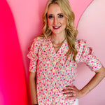 Pink floral button-down top with puff sleeves, colorful blooms, and tied-back detail in breathable cotton.