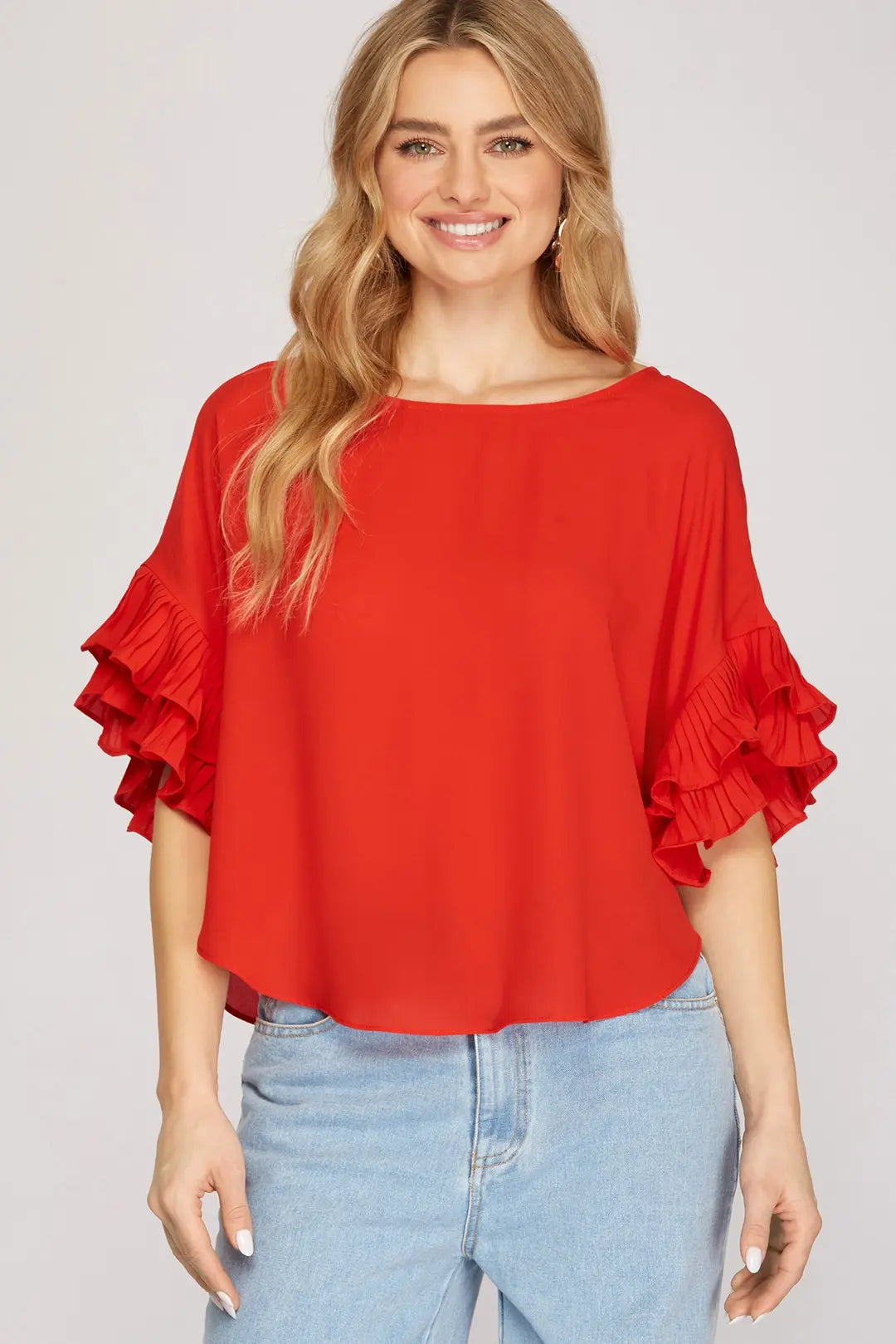 A vibrant red woven top featuring dramatic, multi-tiered pleated ruffle sleeves.
