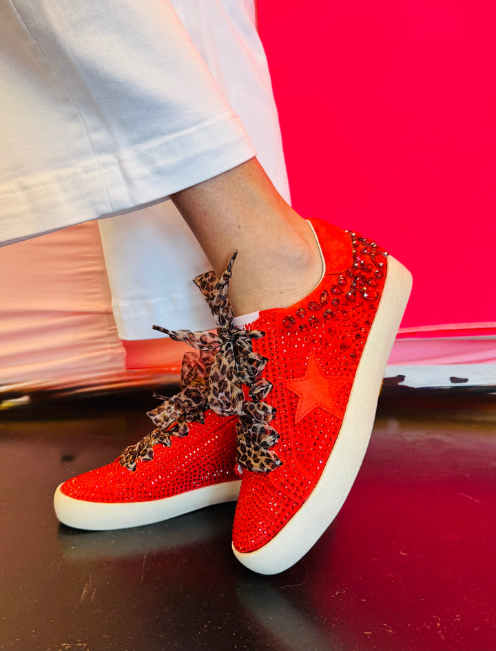 Side profile of red vegan leather sneaker featuring a bold rhinestone star embellishment and slight platform heel with leopard laces.