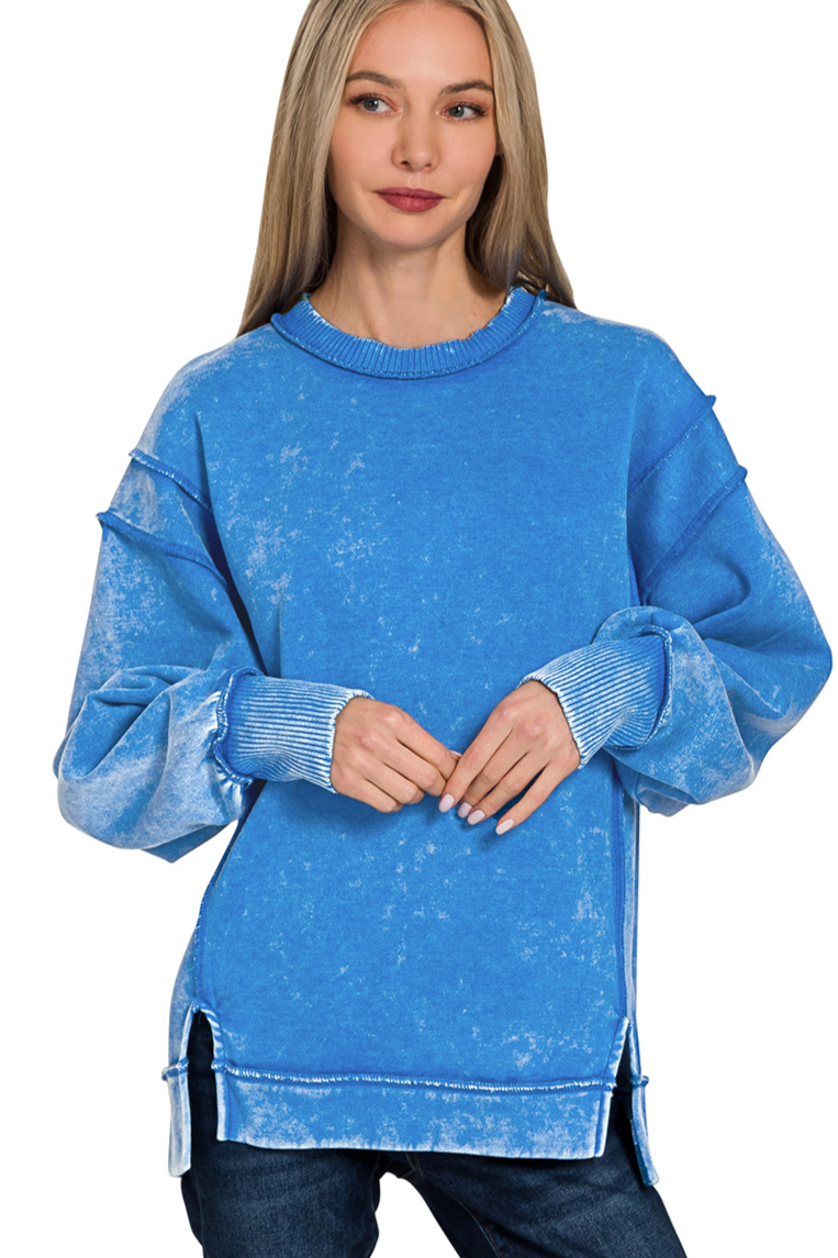 A relaxed-fit, ocean blue acid wash fleece sweatshirt. The sweatshirt has visible exposed seams and a side slit at the bottom.