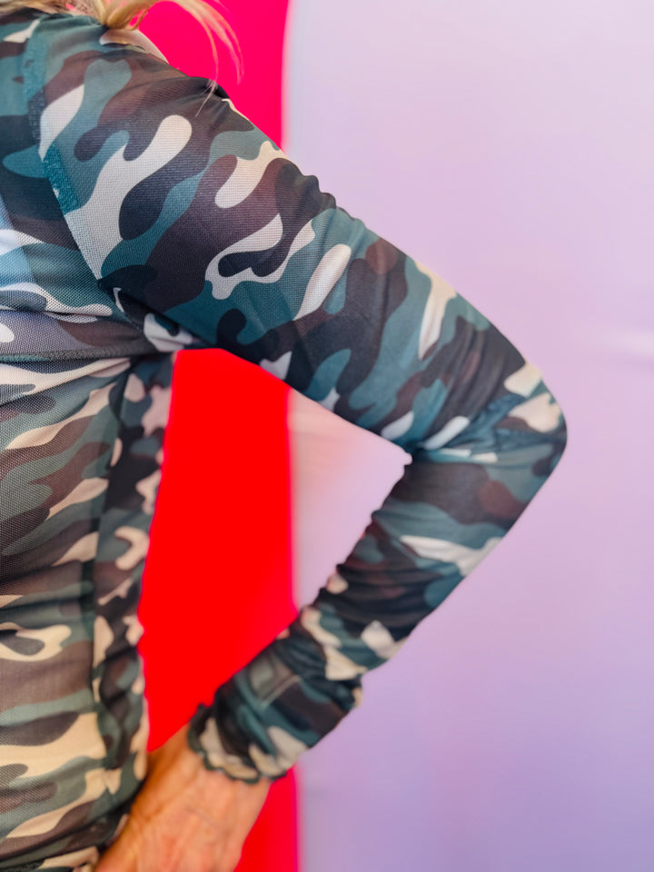 Close-up of the sleeve on the Keigan Mesh Top showing the green camo print, soft stretch mesh fabric, and delicate lettuce-edge hem detail.