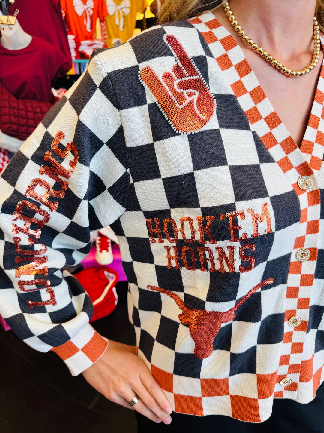 Close up of Queen of Sparkles UT orange and black checkered cardigan with sequin and beading and rhinestone buttons.