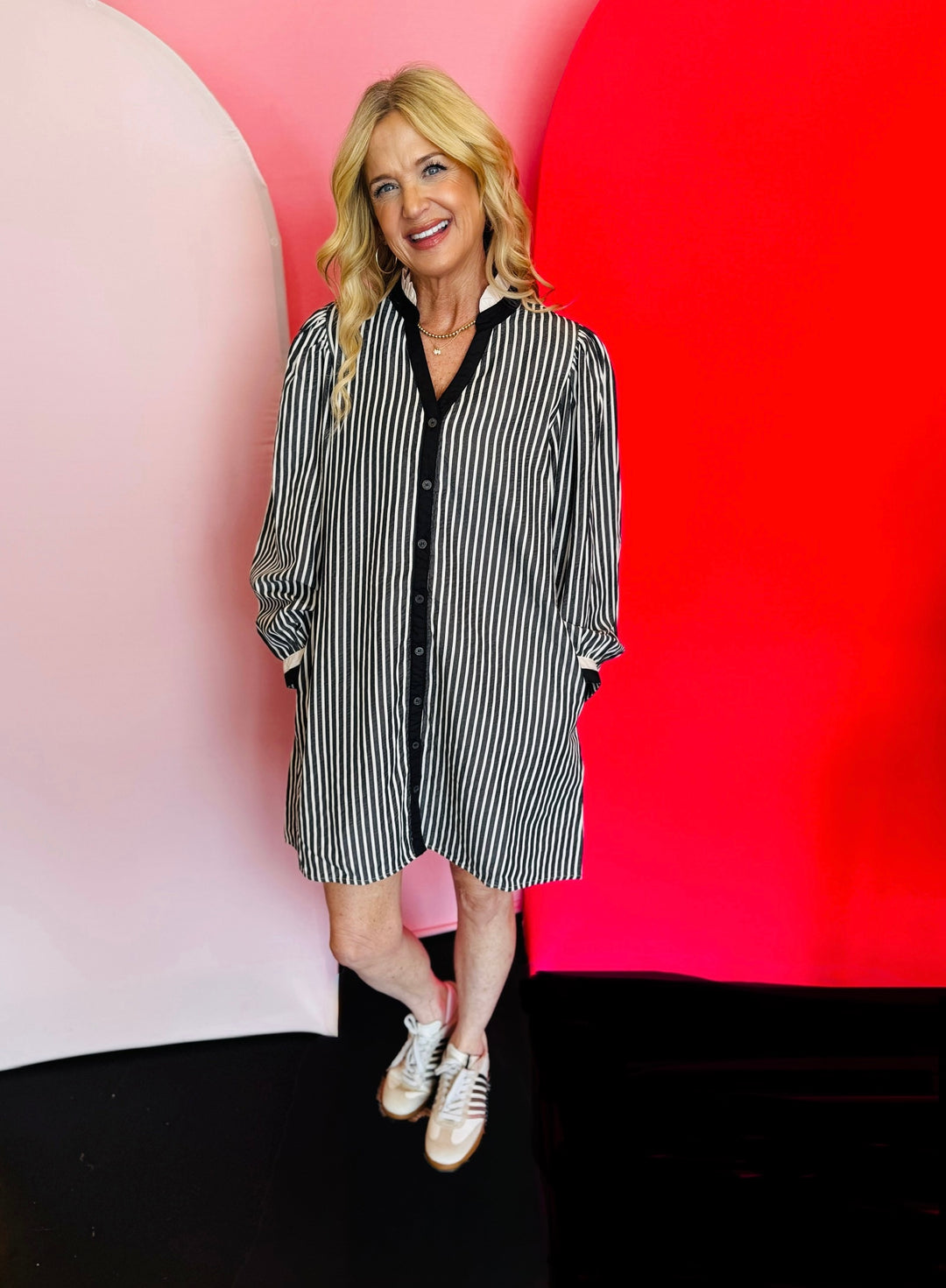 Black and white vertical stripe shift dress with ruffled neckline, long puff sleeves, full button-down front, and side pockets. Fabric blend of polyester, tencel, and cotton.