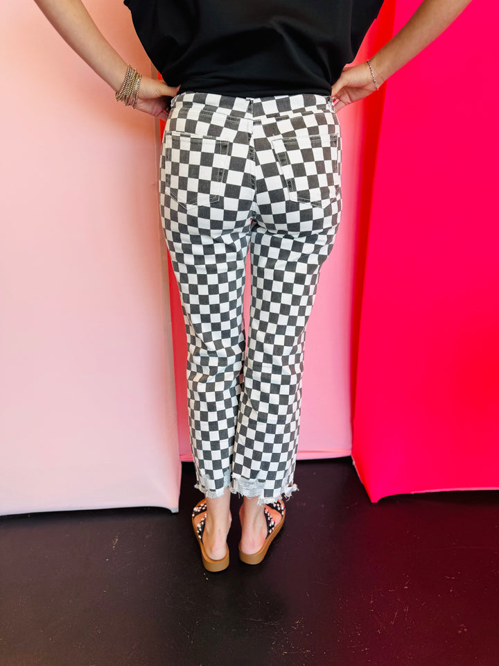 Back view of black and white cropped checkered jeans with knee distressing.