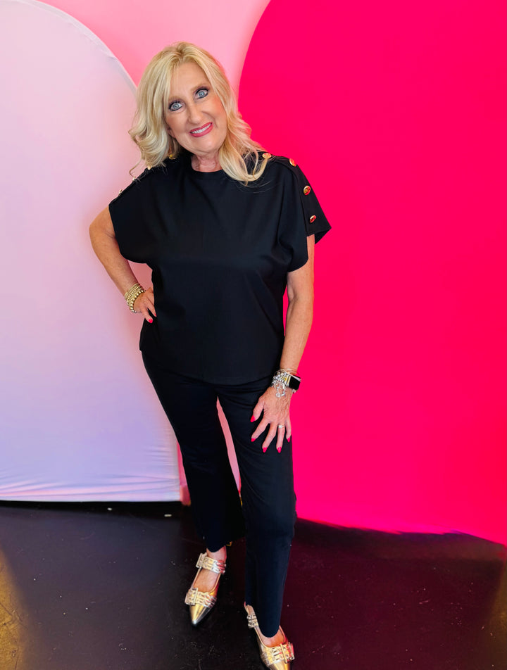 Full outfit view featuring the black crewneck top styled with black pants, showcasing a polished, monochromatic look.
