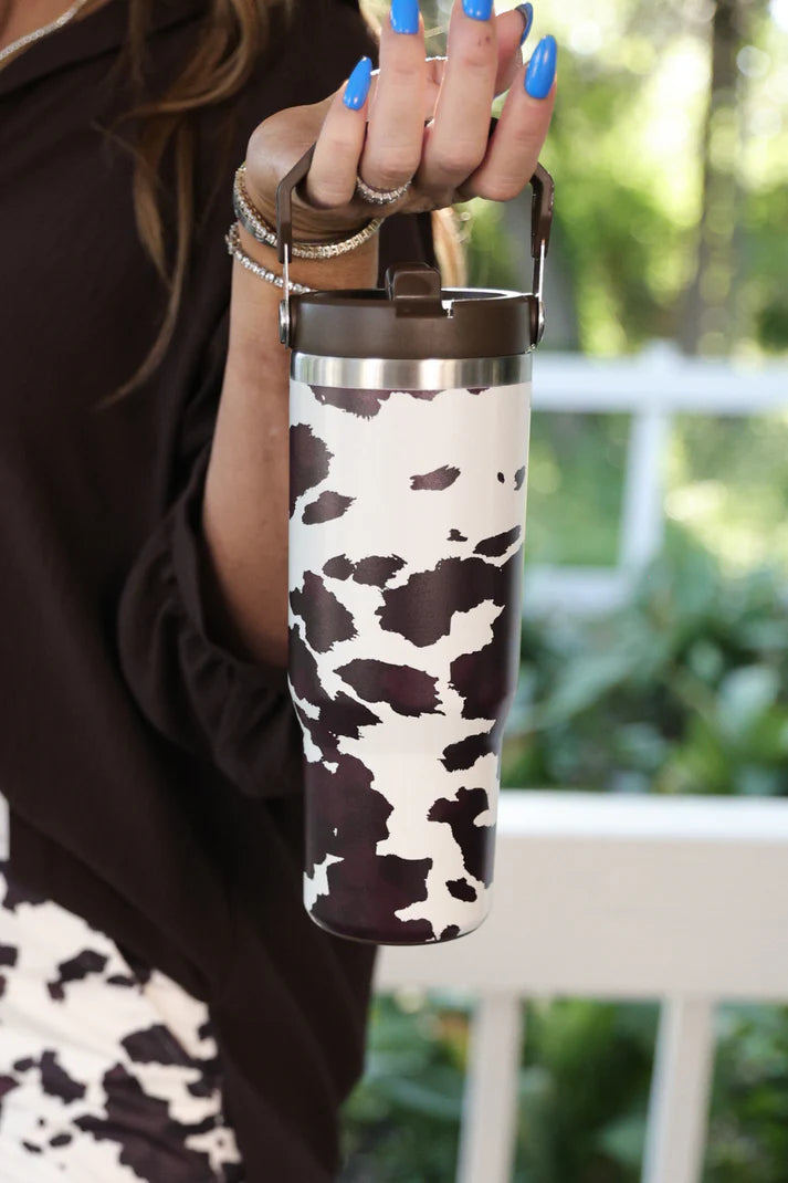 30oz chocolate cow print travel tumbler with screw-on lid, handle, and car cup holder–friendly design.