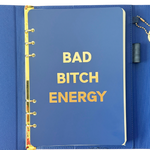 Front page of blue clutch journal folio and calendar with 'BAD BITCH ENERGY' text and colored pen.
