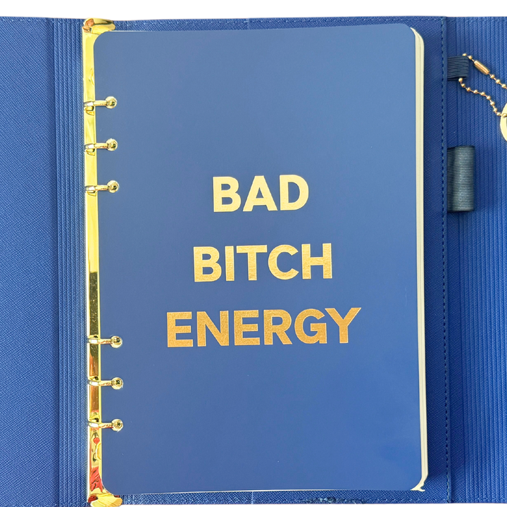 Front page of blue clutch journal folio and calendar with 'BAD BITCH ENERGY' text and colored pen.