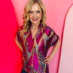 Orchid, gold, and jewel-tone swirl print top with split neckline and short sleeves.