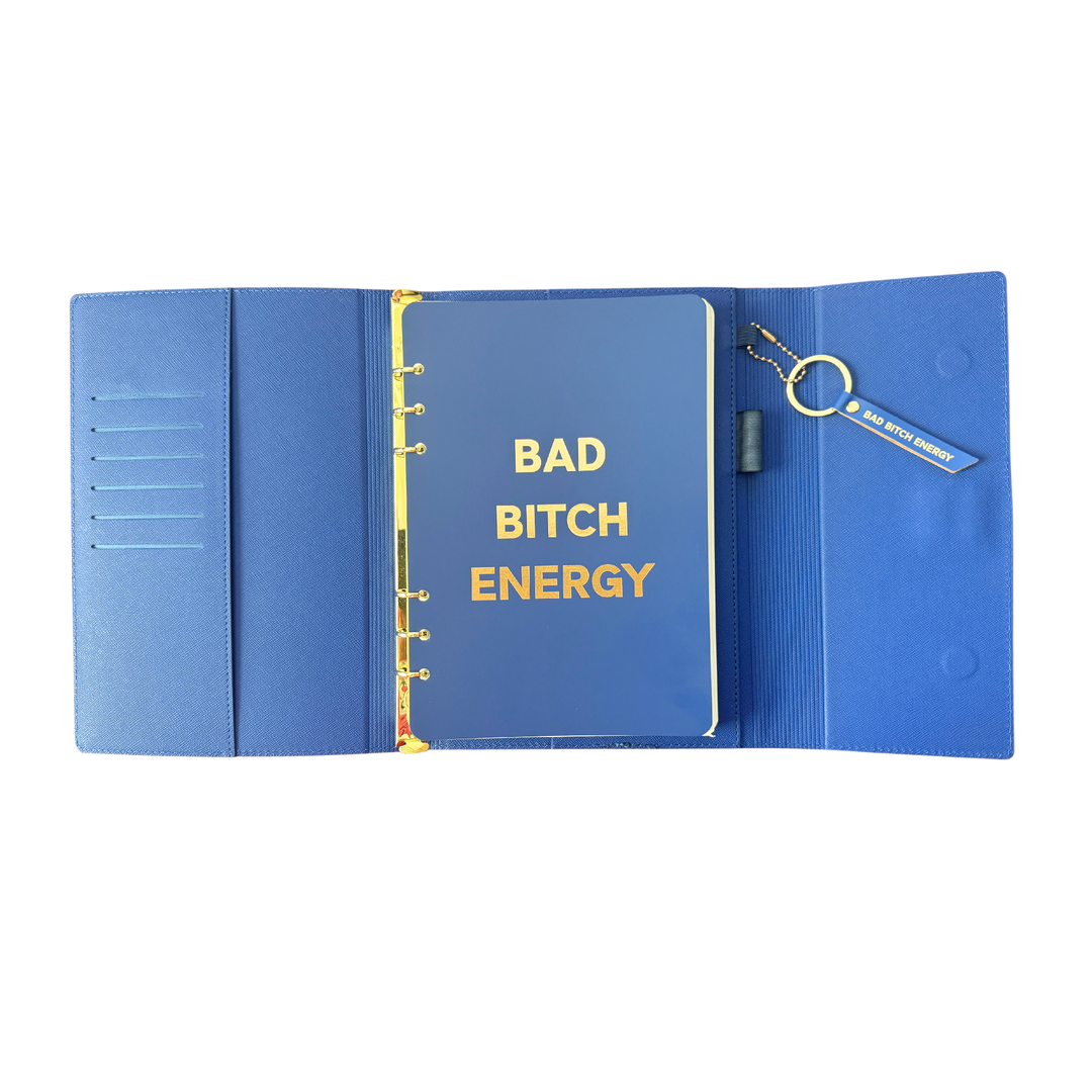 Inside view of blue clutch journal folio and calendar with 'BAD BITCH ENERGY' text and colored pen.