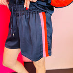 Navy shorts with bold pink and orange side stripes and a high elastic waistband.