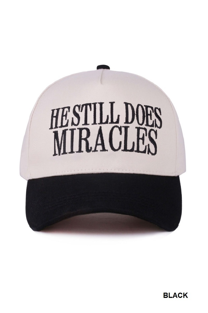Black and white two-tone cap with “He Still Does Miracles” embroidered on the front.