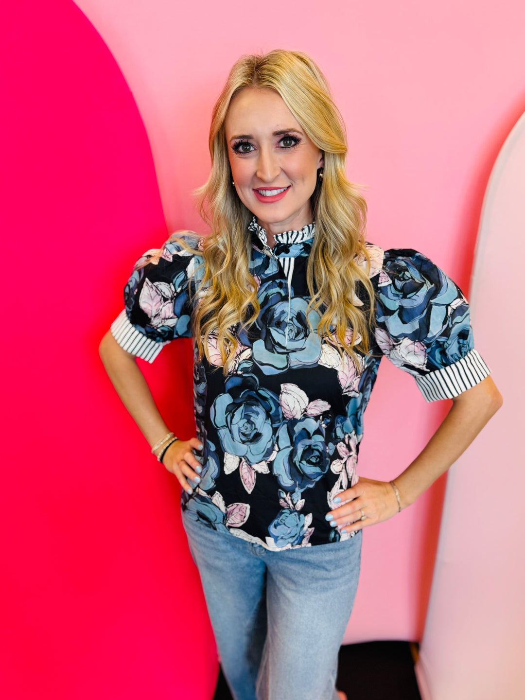 Navy ruffled mock neck floral top with short sleeves, stripe contrast trim, and pastel floral print.